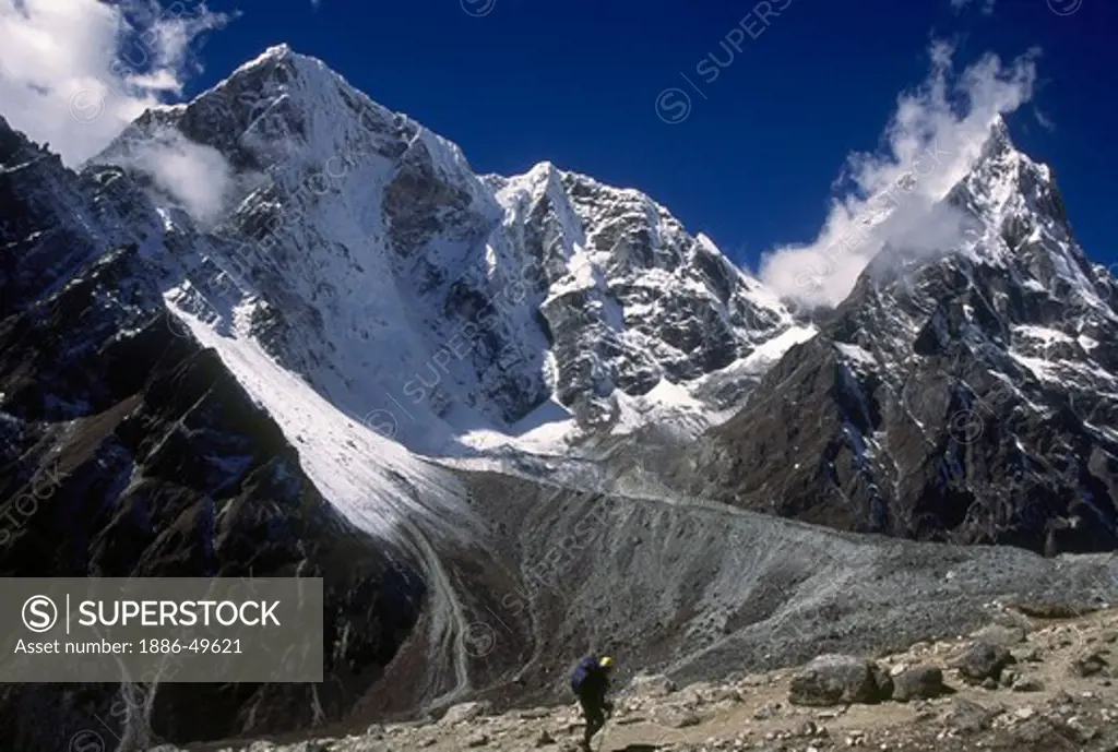 A trekker walks past the mighty wall of Cholatse on the way to Lobuche from Dingboche; Everest region; Khumbu valley; Nepal
