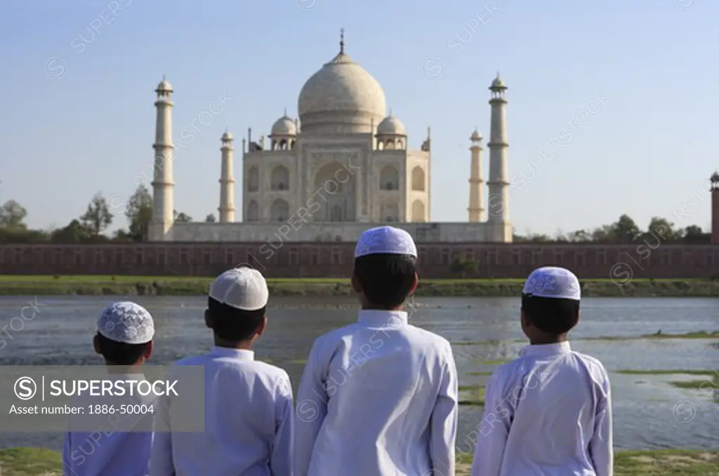 Young muslim boys performing religious prayer Namaz in front of Taj Mahal Seventh Wonders of World on south bank of Yamuna river ; Agra ; Uttar Pradesh ; India UNESCO World Heritage Site