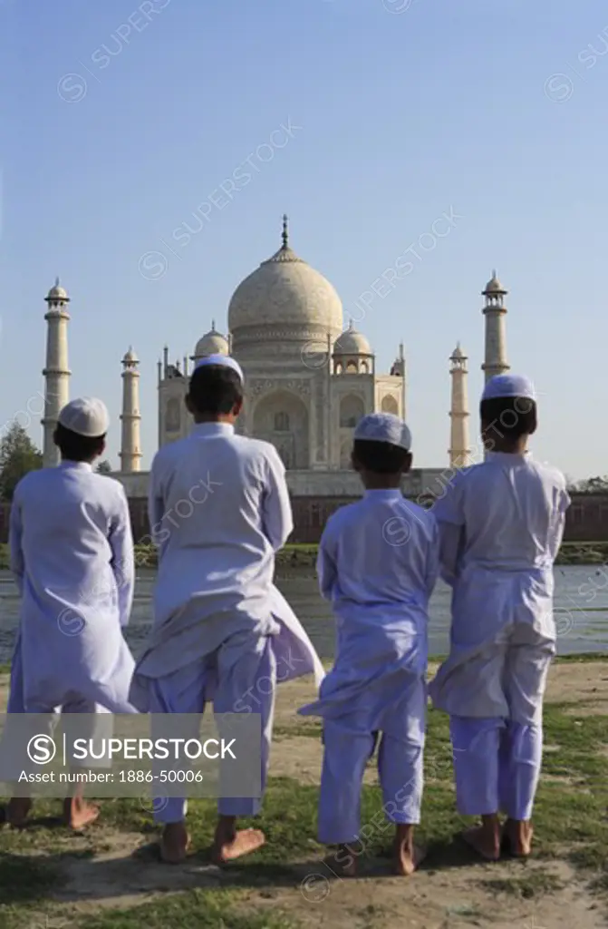 Young muslim boys performing religious prayer Namaz in front of Taj Mahal Seventh Wonders of World on south bank of Yamuna river ; Agra ; Uttar Pradesh ; India UNESCO World Heritage Site