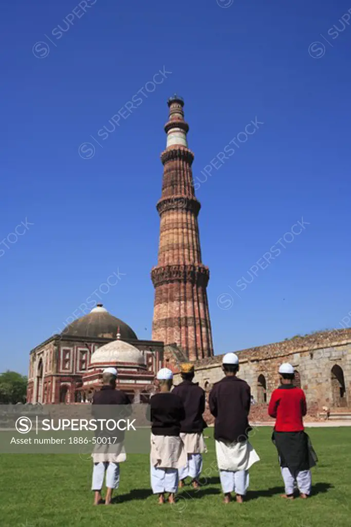 Children doing Namaz in front of Alai Darwaza ; Imam Zamin's tomb and Qutab Minar built in 1311 red sandstone tower ; Indo-Muslim art ; Delhi sultanate ; Delhi ; India UNESCO World Heritage Site