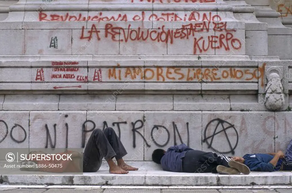 UNEMPLOYED street people in front of GRAFFITI which protests govenrment policies - BUENOS AIRES, ARGENTINA