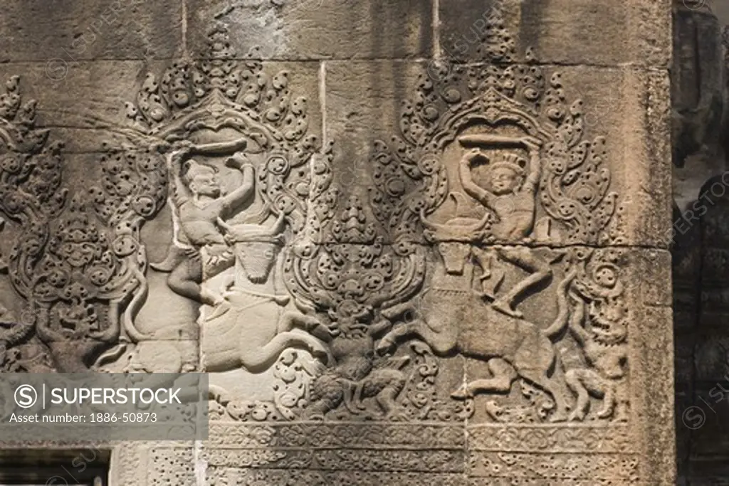 A stone carved bas relief from Hindu mythology of a battle atop bulls at Angkor Wat, built in the 11th century by Suryavarman the 2nd,  -  Cambodia