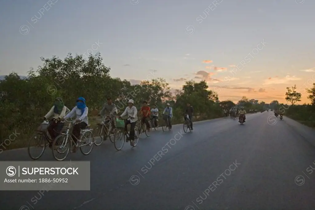 Cambodian workers bicycle to Siem Reap at dawn near  Angkor Wat - Cambodia
