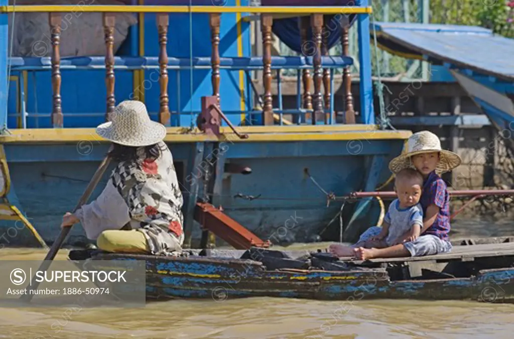 A family poles their boat through the Vietnamese floating village of Chong Kneas on lake Tonle Sap - Siem Reap, Cambodia