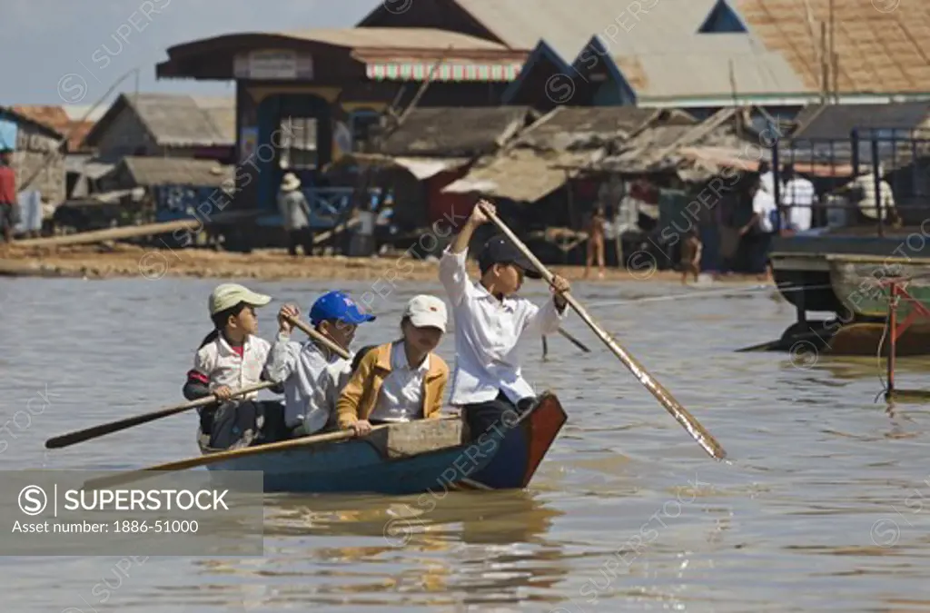 School children row their home in the Vietnamese floating village of Chong Kneas on lake Tonle Sap - Siem Reap, Cambodia