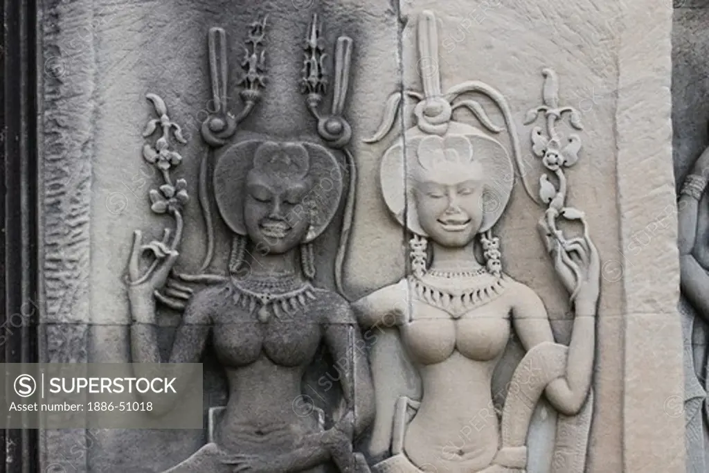 Stone carved bas relief of two smiling Apsaras (celestial maidens) at Angkor Wat, built in the 11th century by Suryavarman the 2nd,  -  Cambodia