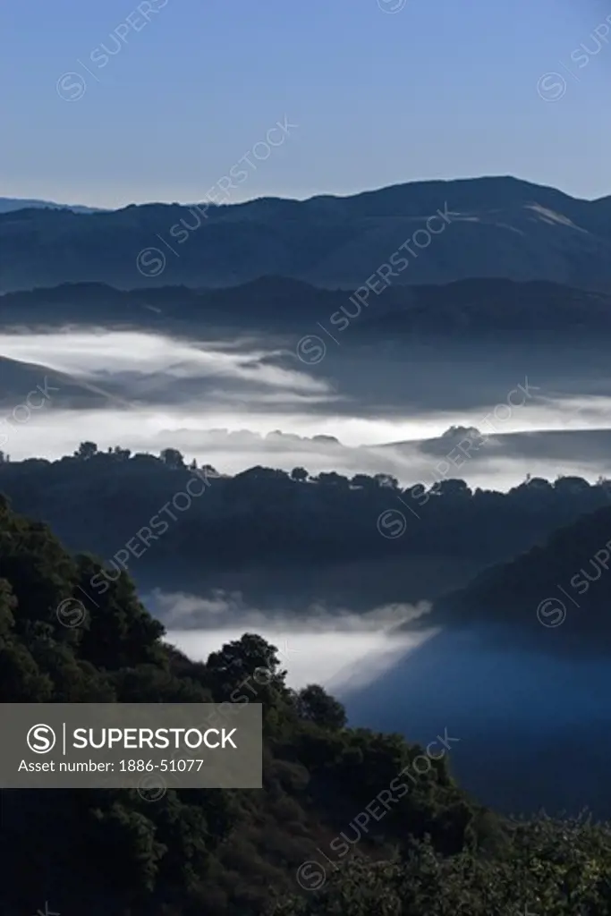 Early morning fog hangs in the low lands below Los Laureles Grade between Carmel Valley and the Salinas Valley - Coastal Mountain Range, California
