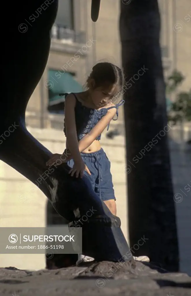 Little girl under a STATUE in the PLAZA DE ARMAS - SANTIAGO, CHILE