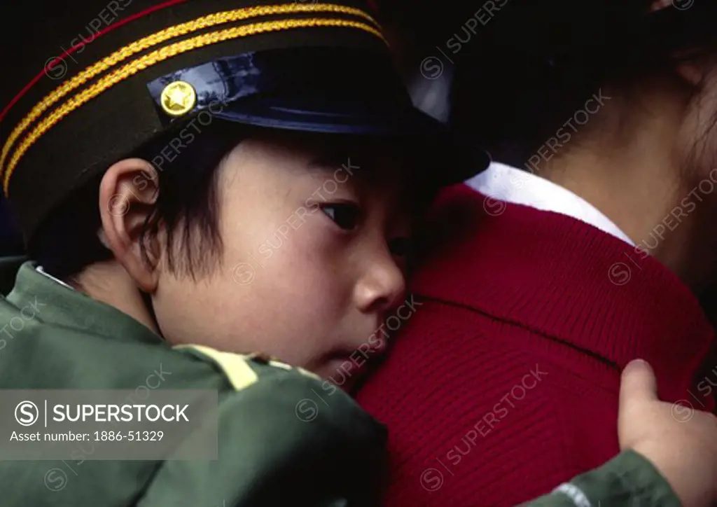 Chinese BOY naps while being held by his mother on the streets of KUNMING - YUNNAN, CHINA