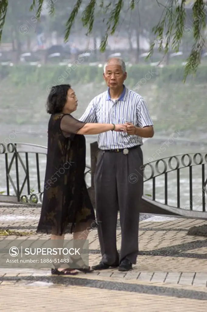 Older Chinese couple practice ballroom dancing in a park along the Jin River - Chengdu, China in Sichuan Province
