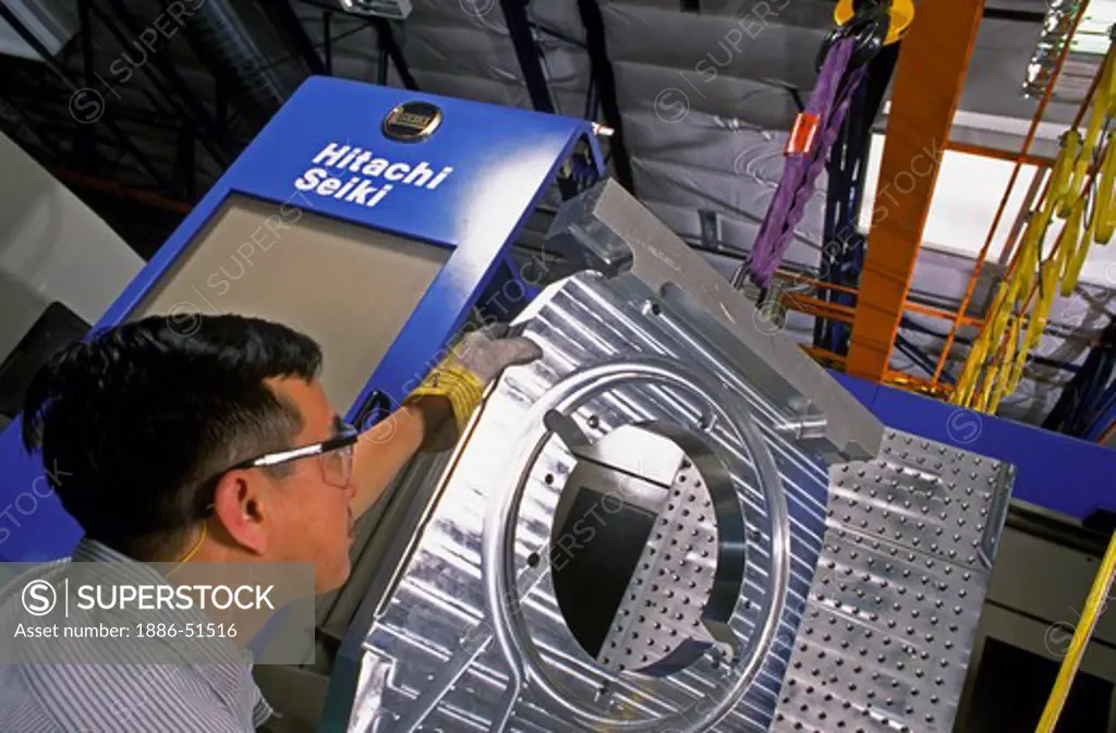Worker moves finely machined ALUMINUM PART in to position for further manufacturing in SILICON VALLEY, CALIFORNIA