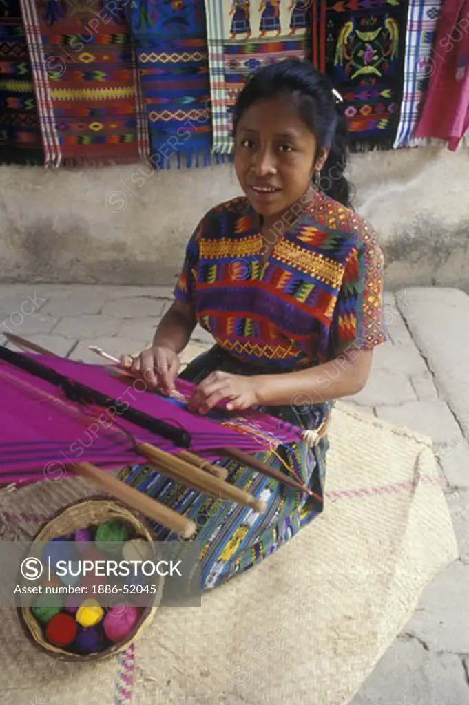 INDIGENOUS WOMAN with traditional BACKSTRAP LOOM weaving a HUIPIL, a traditional bracade cloth - GUATAMALA