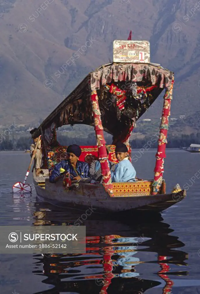 INDIAN TOURISTS take a ride in a SHIKARA, local paddle boat with a canopy, on DAL LAKE in SRINIGAR - KASHMIR, INDIA