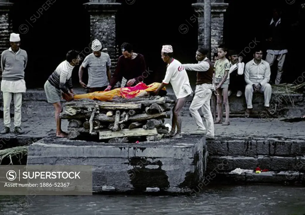 A human body is layed on a CREMATION GHAT at the Hindu Temple complex of PASHUPATINATH where the ashes will be swept into the BAGMATI RIVER - KATHAMANDU, NEPAL