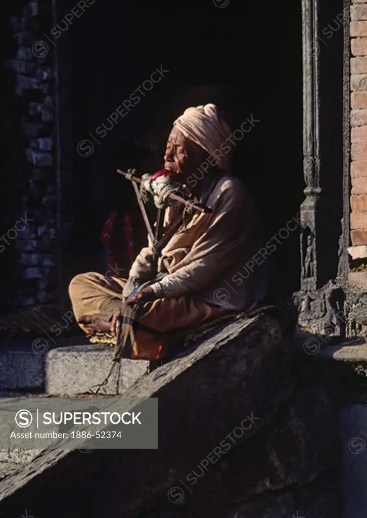 A NEPALI MAN with a home made crutch suffers from physical pain - PASHUPATINATH TEMPLE COMPLEX, KATHAMANDU, NEPAL
