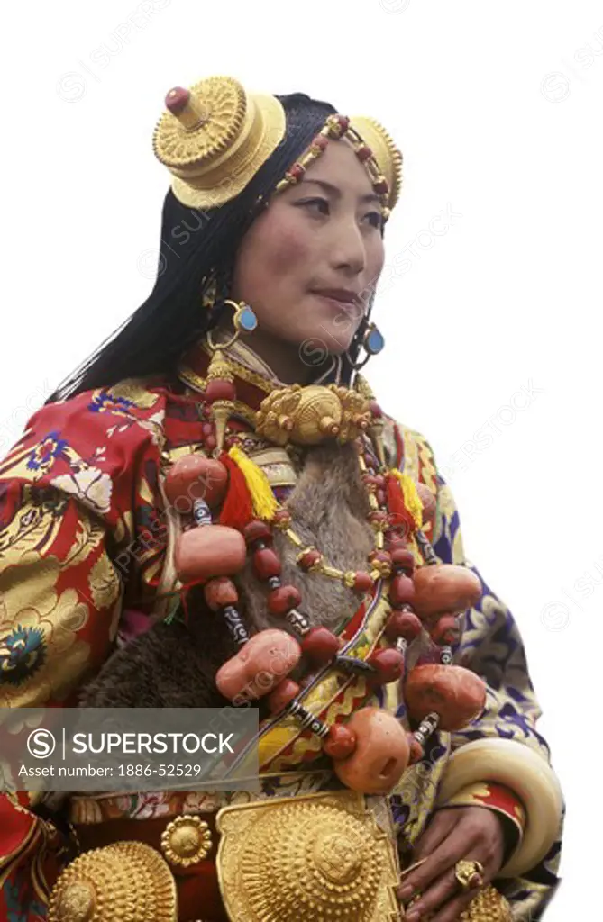 Female Khampa wears gold hair pieces & gau boxes, zee stones & coral at the Litang Horse Festival - Sichuan Province, China