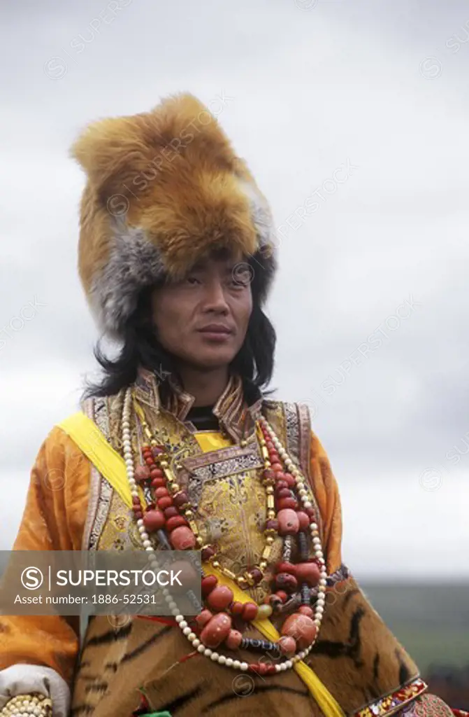 Male Khampa wears coral, zee stones, fox fur hat & tiger skin at the Litang Horse Festival - Sichuan Province, China, (Tibet)