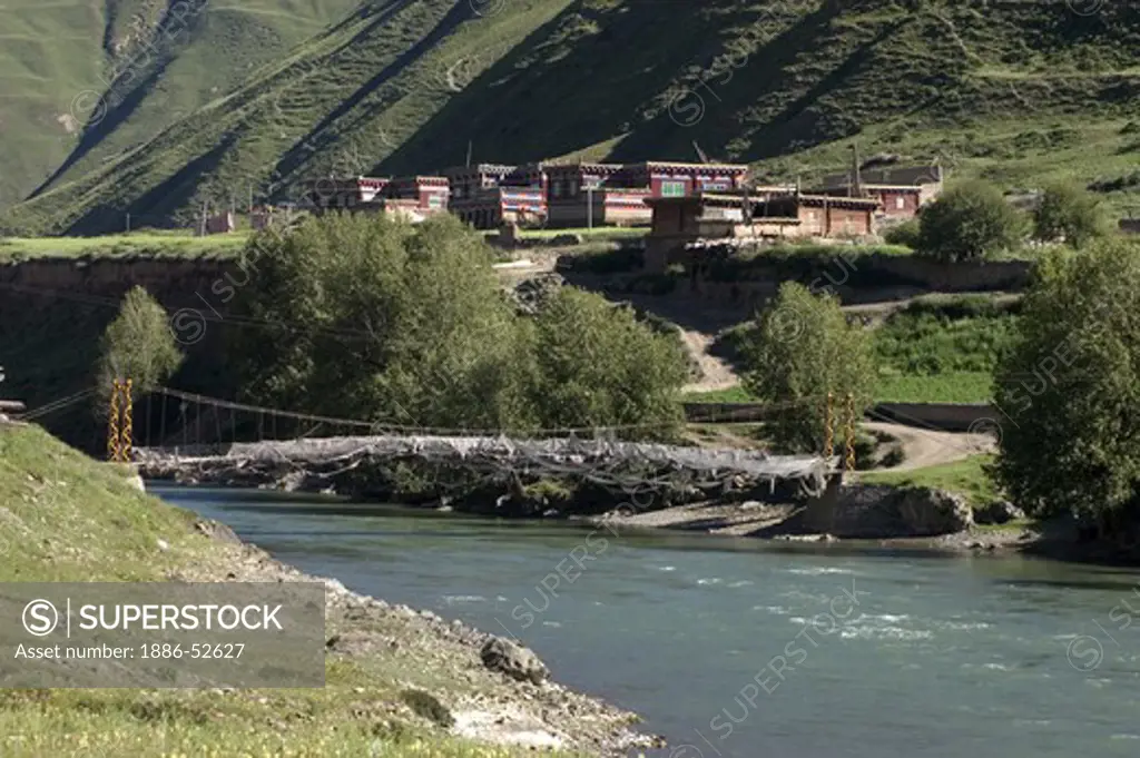 Tibetan stlye houses, a flowing river and green summer hills - Kham (Eastern Tibet), Sichuan Province, China