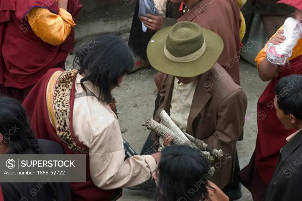 Khampa examines traditional knives at the Cham dances, Katok Dorjeden Monastery - Kham, (eastern, Tibet), Sichuan, China