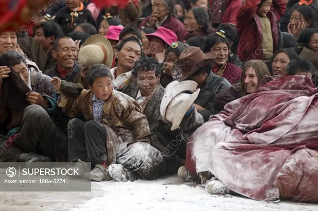 Crowd is covered with flower as a prank of the arhat clown, Monlam Chenmo, Katok Monastery - Kham, (Tibet), Sichuan, China