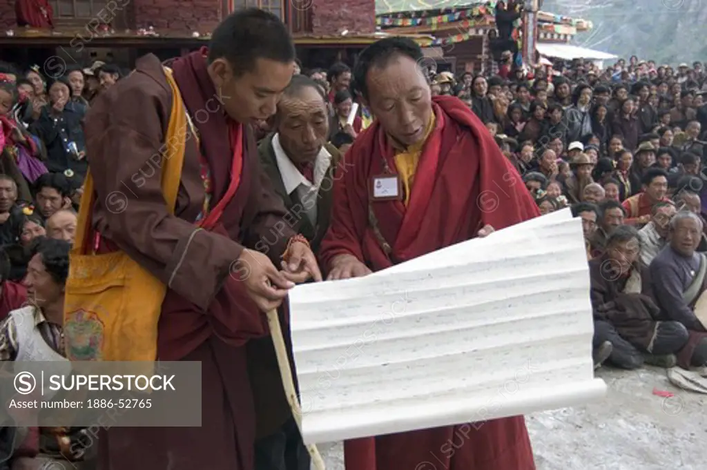 Buddhist monks hold scriptures at the Monlam Chenpo, Katok Dorjeden Monastery - Kham, (Tibet), Sichuan, China