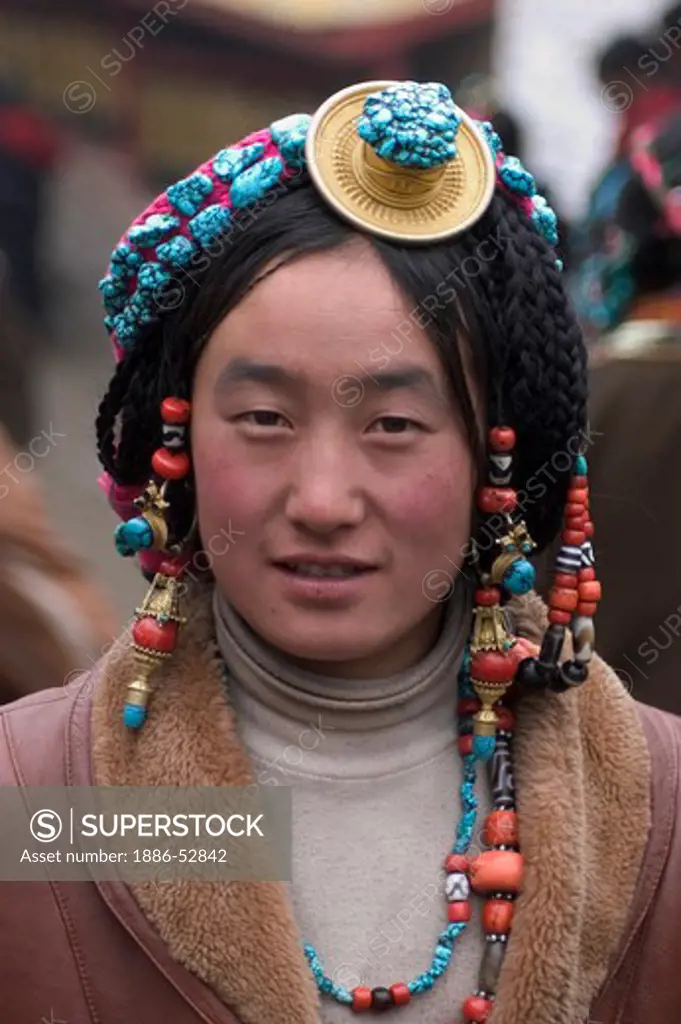 Khampa woman wears a gold and turquoise hair piece at the Monlam Chenpo, Katok  Monastery - Kham, (Tibet), Sichuan, China
