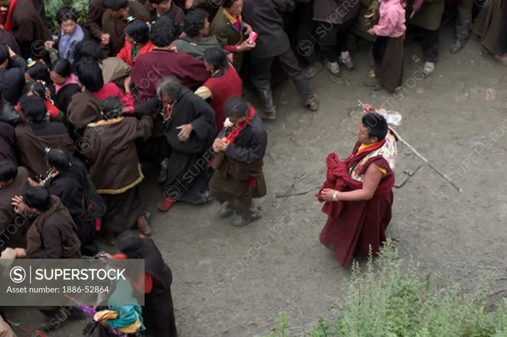Buddhist monk beats crowd back with a stick during the Cham dances at Katok  Monastery - Kham, (Tibet), Sichuan, China