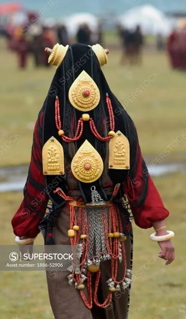 Detail of traditional female Khampa wearing gold & coral hair peices at the Litang Horse Festival - Sichuan Province, China (Tibet)