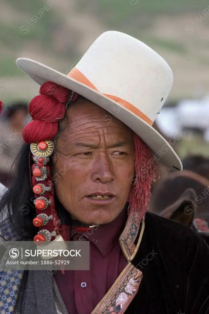 Khampa with jaunty cowboy hat and ivory hair peices at the  Litang Horse Festival  in Kham - Sichuan Province, China, (Tibet)