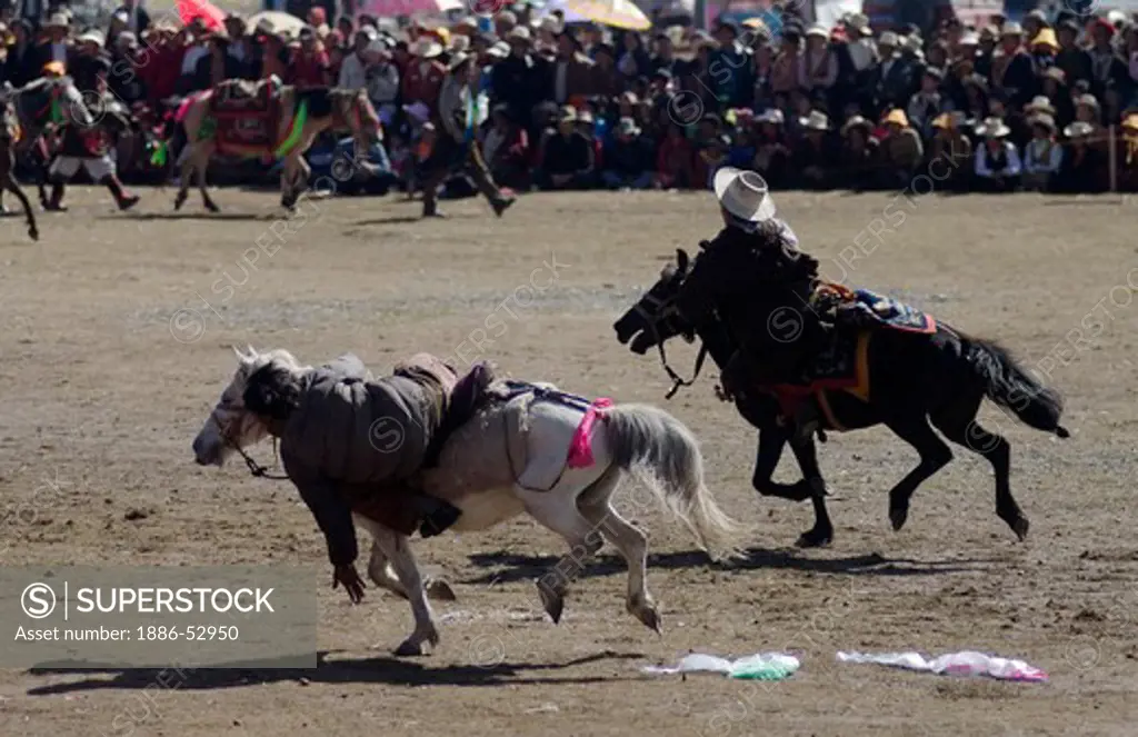 Khampas pick up Kathoks from the ground on horseback at the Litang Horse Festival in Kham - Sichuan Province, China, (Tibet)