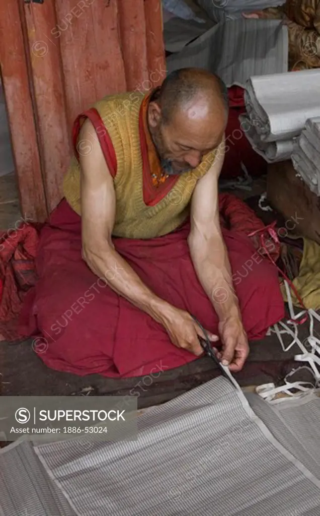 A Buddhist monk trims a sacred text at a monastery in Dabpa County, Kham - Sichuan Province, China, (Tibet)
