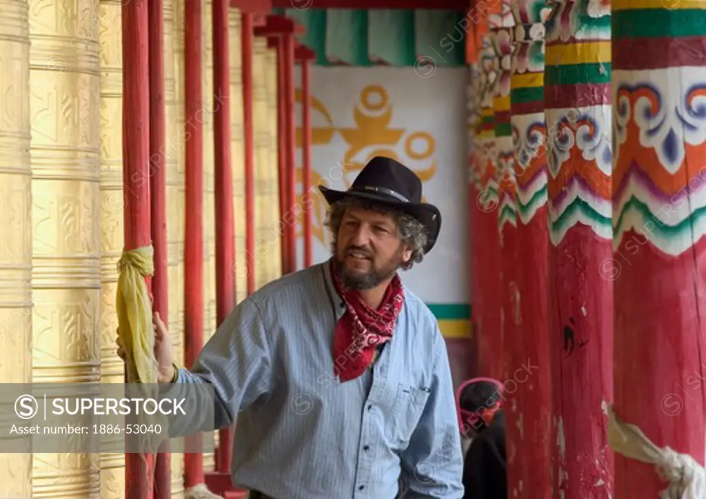 Man turns giant prayer wheels at the Buddhist Monastery of Tagong (Lhagang) - Kham, Sichuan Province, China, (Tibet)