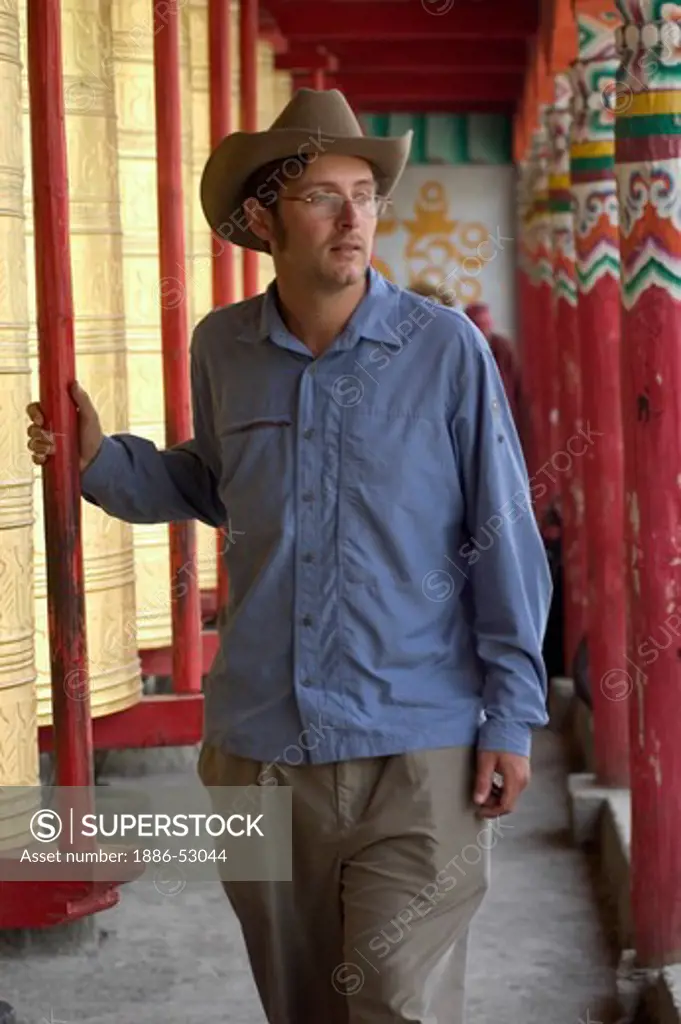 American man turns giant prayer wheels at the Buddhist Monastery of Tagong (Lhagang) - Kham, Sichuan Province, China, (Tibet)