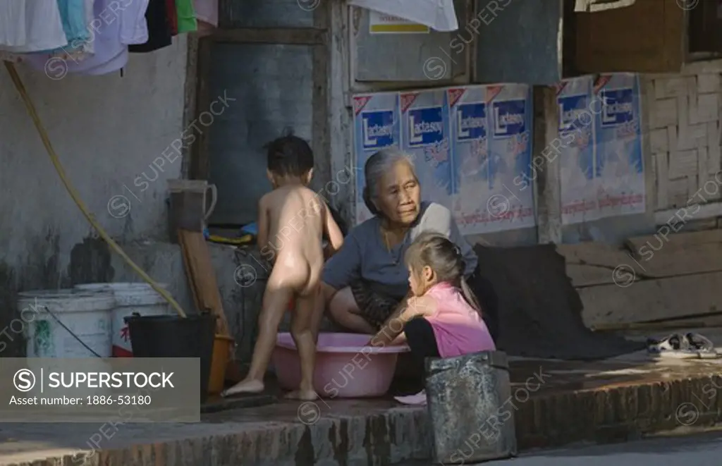 A Laotian grandmother baths her grandchildren in the former French Provincial town of LUANG PROBANG - LAOS