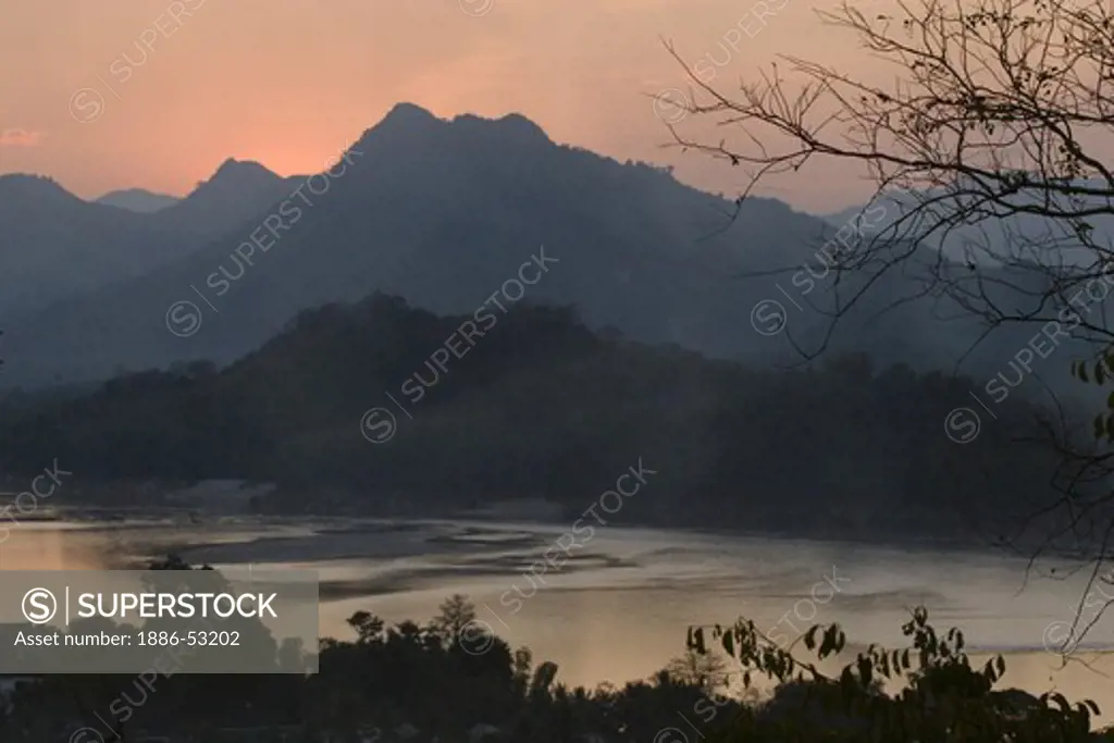 The sun sets over a hill on the Mekong River in the former Provincial town of LUANG PROBANG - LAOS