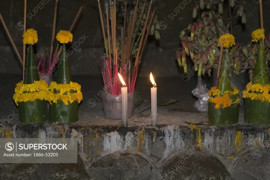 Flowers and candles at a Buddhist shrine in the former Provincial town of LUANG PROBANG - LAOS