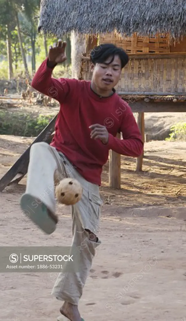 Young Laotian man plays kick ball in LUANG PROBANG - LAOS