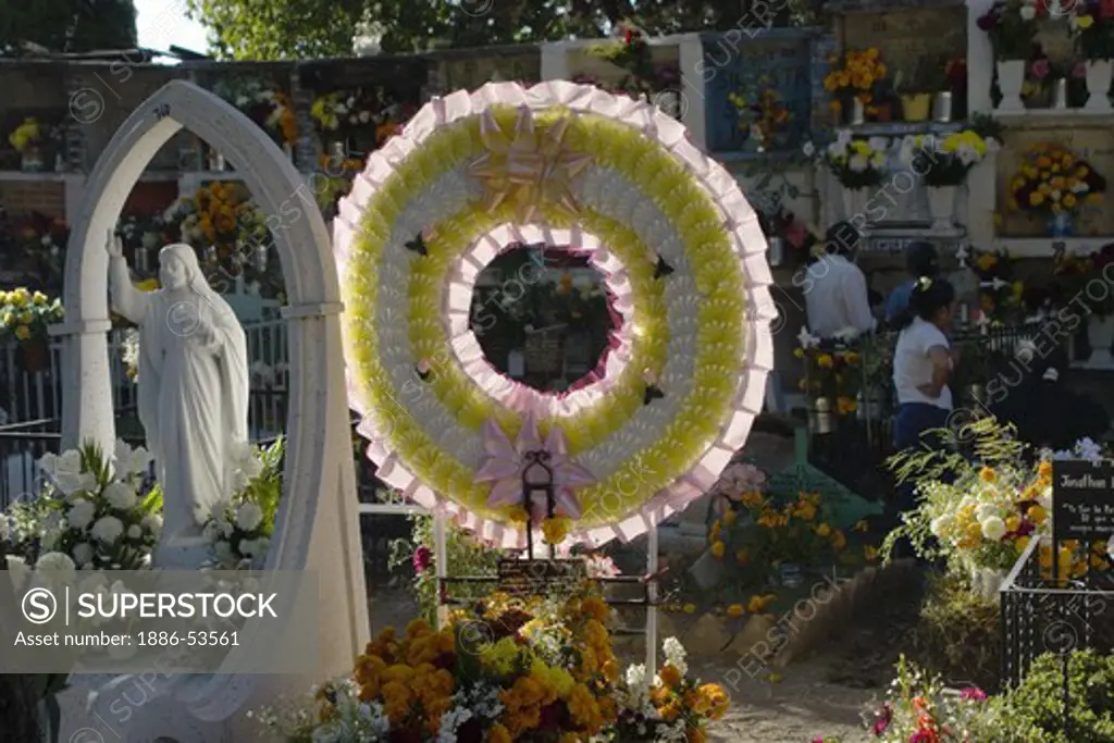 FLOWER COVERED GRAVES and JESUS STATUE at the local cemetery during the DEAD OF THE DEAD - SAN MIGUEL DE ALLENDE, MEXICO