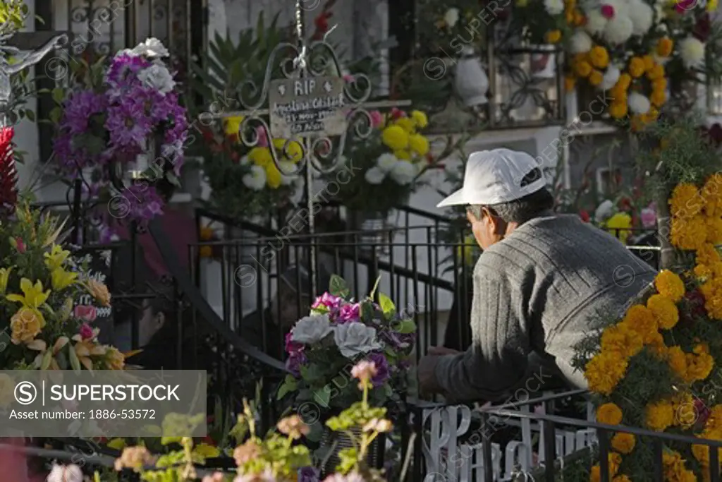 A MEXICAN man communes with a relative at the cemetery during the DEAD OF THE DEAD - SAN MIGUEL DE ALLENDE, MEXICO