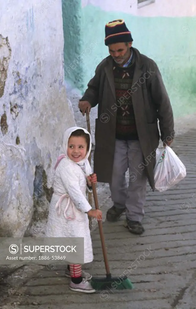 A young GIRL SWEEPS the cobblestones in the MEDINA in CHECHAOUEN in the RIF MOUNTAINS of northern MOROCCO