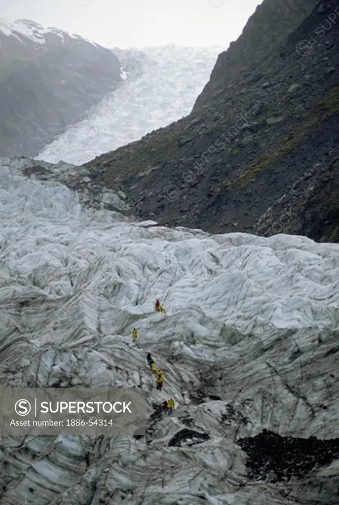 Visitors explore the FOX GLACIER, one of the worlds few advancing glaciers - SOUTH ISLAND, NEW ZEALAND