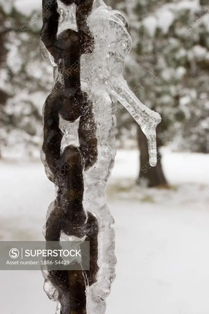 Ice freezes on a metal chain used to drain waterfrom a roof during the winter - BEND, OREGON