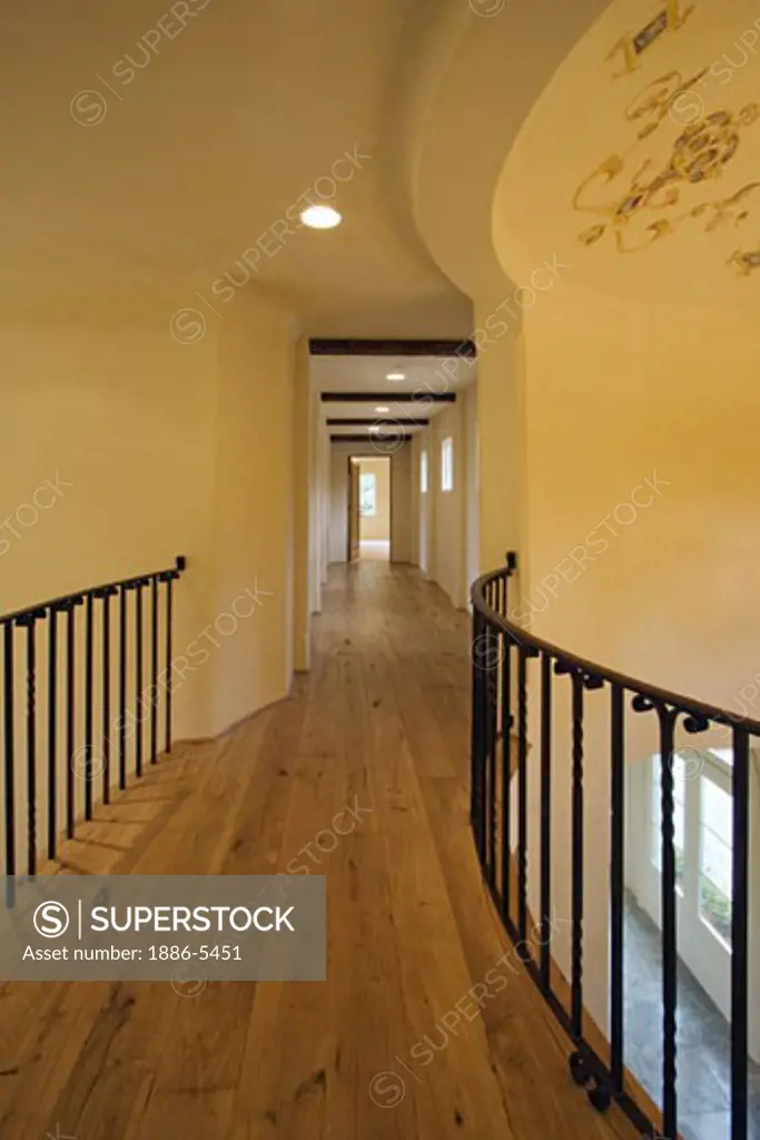 HARDWOOD FLOOR and wrought iron RAILING in the upstairs hallway of a CALIFORNIA LUXURY HOME 
