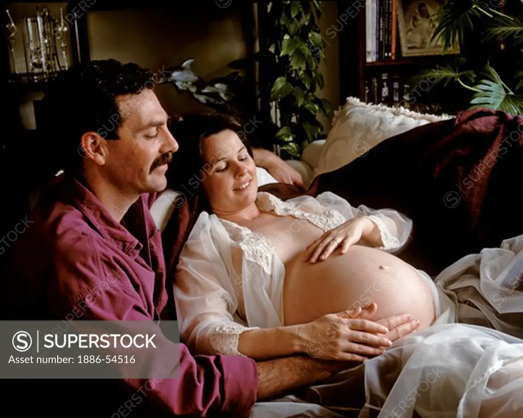 A father to be shares a special moment with his very PREGNANT WIFE - model released