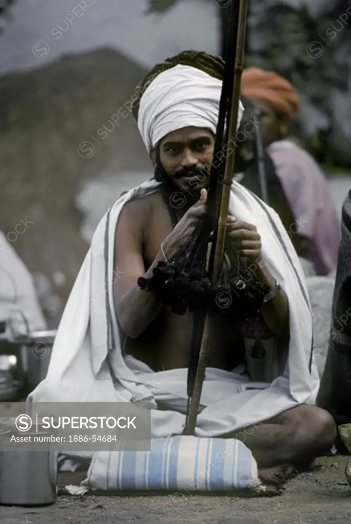 A HINDU SADDHU WEAVES CLOTH while on PILGRIMAGE at the PUSHKAR CAMEL FAIR, a 5 day religious festival - RAJASTHAN, INDIA