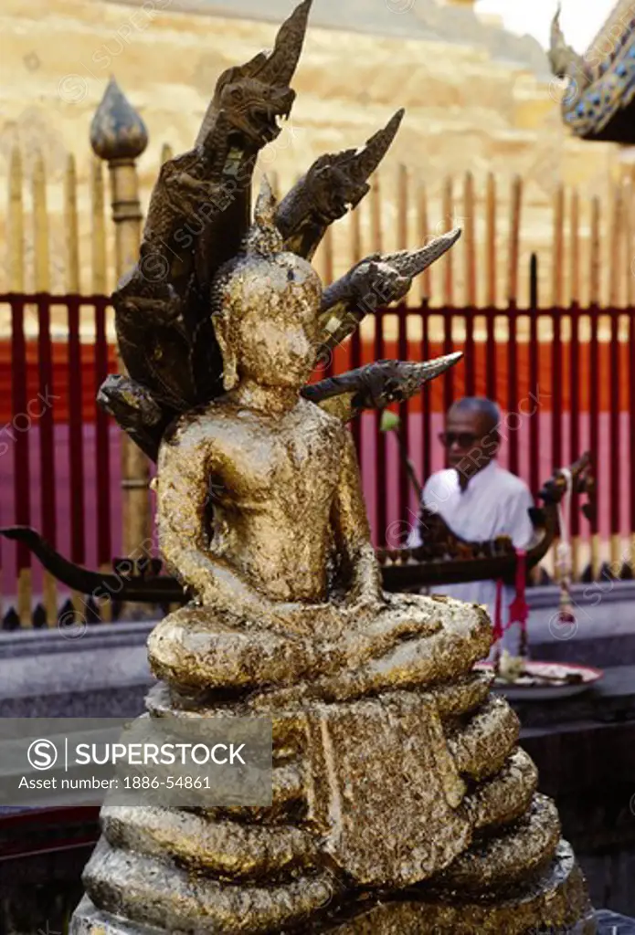 GOLD LEAF is pressed onto Buddhist statues at WAT PRATHAT (Doi Suthep) as donations - CHIANG MAI, THAILAND