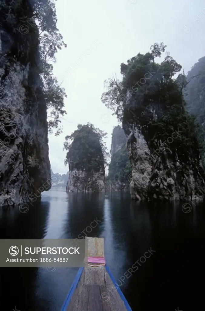 Boating in the KHAO SOK NATIONAL PARK, a large reservoir surrounded by limestone cliffs in a rain forest - THAILAND