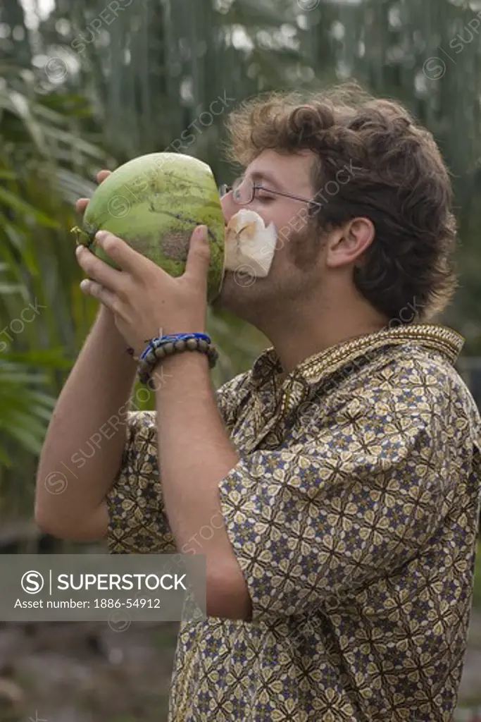 Visitor drinks from a coconut in the village of Tung Nang Dam located on the North Andaman Sea - THAILAND
