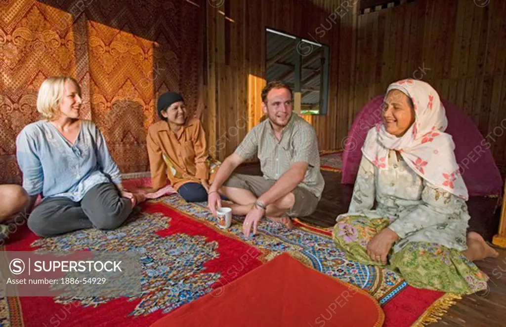 Eco tourists talk with a Thai woman during a home stay in the  village of Ban Talae Nok located on the North Andaman Sea - THAILAND