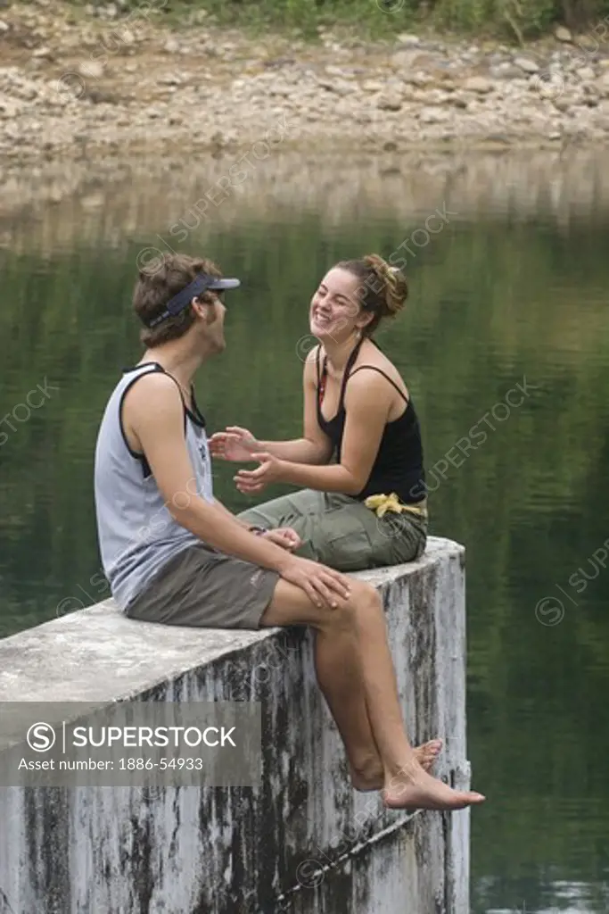 Young couple enjoy  a conversation at the dam and reservoir near Kuraburi, a town on the North Andaman Coast - THAILAND